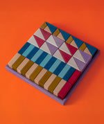 Grimm's wooden rhythm hand crafted pieces in a purple square frame against a orange background