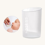 Cup from the Haakaa colostrum collector feeding pack shown alongside a baby being bed using the cup.