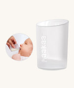 Cup from the Haakaa colostrum collector feeding pack shown alongside a baby being bed using the cup.