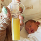 Close up of a filled colostrum soratge tube from the Haakaa colostrum collector feeding pack. Baby in the background. 