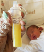 Close up of a filled colostrum soratge tube from the Haakaa colostrum collector feeding pack. Baby in the background. 