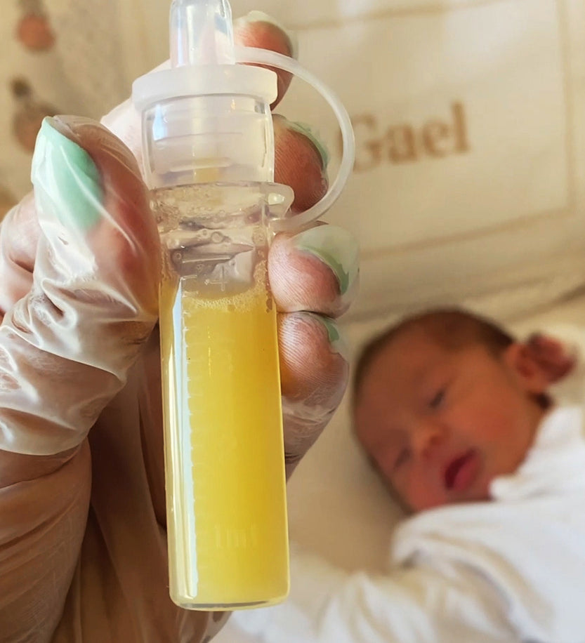 Close up of a filled colostrum soratge tube from the Haakaa colostrum collector feeding pack. Baby in the background. 