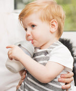 A child drinking from a Haakaa Baby Bottle, using the Generation 3 
 Silicone Bottle Handle in grey