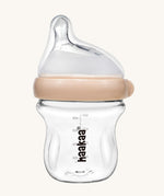 The Haakaa Generation 3 Glass Baby Bottle 120ml in peach, on a cream background