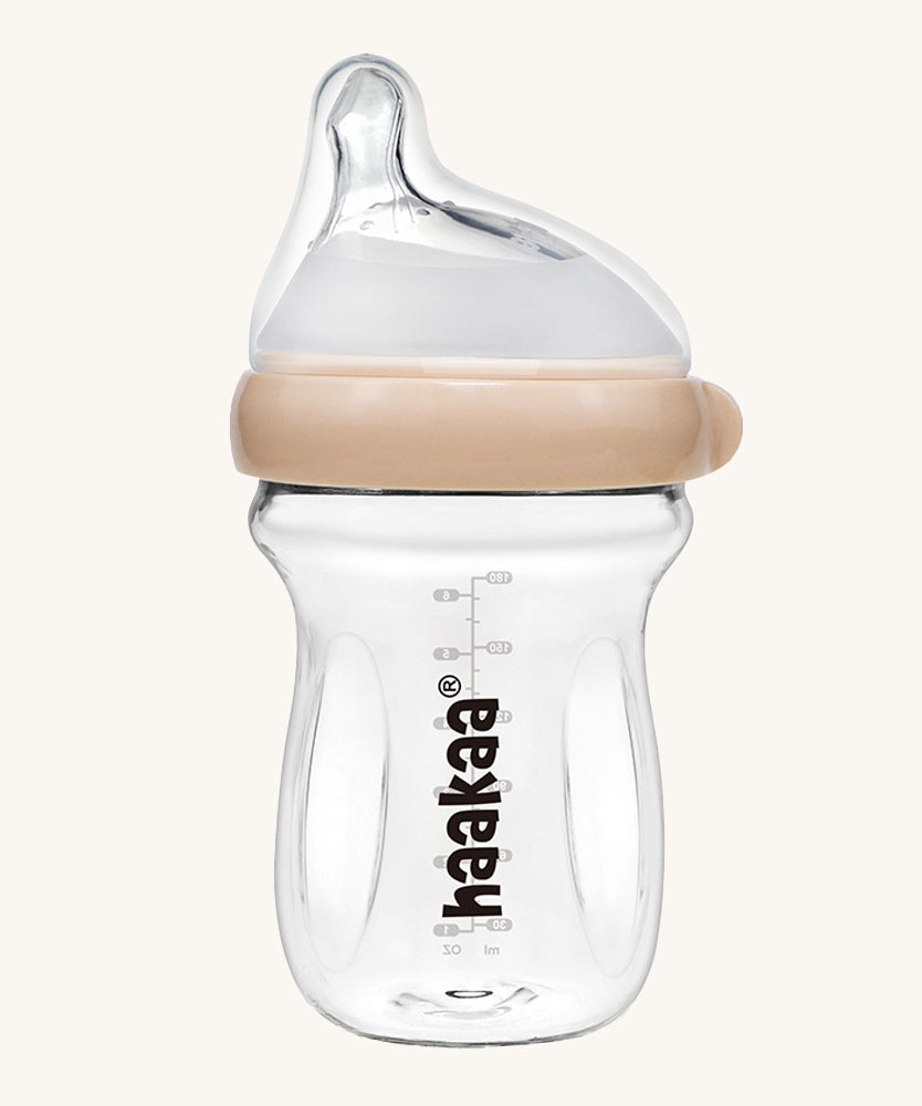 The Haakaa Generation 3 Glass Baby Bottle 180ml in peach, on a cream background