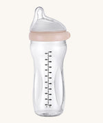The Haakaa Generation 3 Glass Baby Bottle 300ml in peach, on a cream background