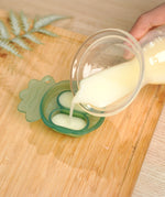 A person pouring breast milk into the Haakaa silicone Nibble Tray from the Haakaa Freeze-N-Feed Mini Set