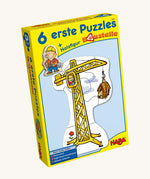 A yellow cardboard box with a picture of a crane on the front for the Haba 6 construction jigsaw puzzle sets on a cream background