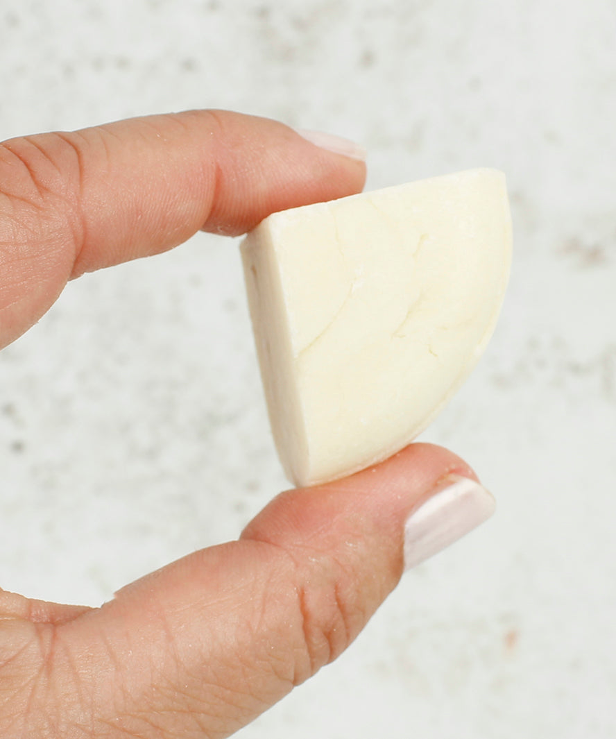 A person holding a piece of the Shower Blocks 1/4 Bar Sample - Sweet Orange & Bergamot