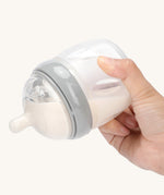 A person is tipping a Haakaa baby bottle with the Generation 3 Silicone Bottle Anti-Colic Nipple, to show that it doesn't drip when upside down