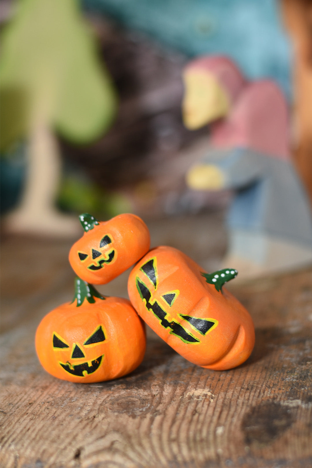 Halloween Scene of Three small wooden orange pumpkins with black faces on a wooden surface, blurred background