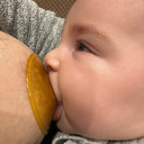 Hevea Natural Rubber Nipple Shields on a breast with baby feeding. 