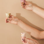 Three sizes of Hevea LOOP menstrual cups being held up.