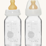A pack of two Hevea glass baby bottles 120ml with natural rubber teats, one with the dust cap, one without. 