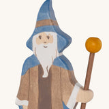 A close up of the Holztiger wooden bearded magician figure showing the hand painted facial features and blue hat while holding  a wooden staff