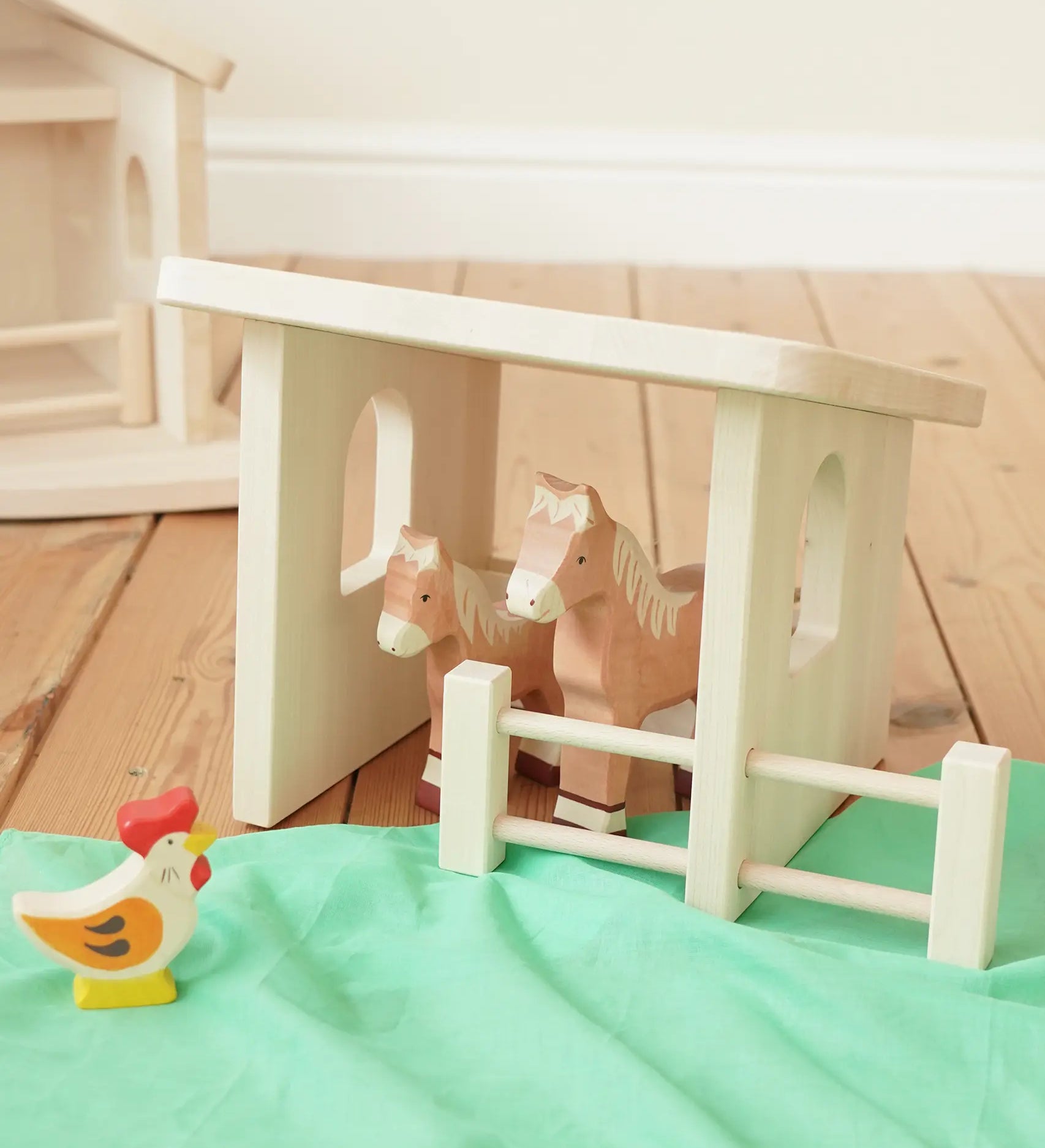 Holztiger wooden shelter toy for farm animals with moving fence door, windows and feeing trough with light brown Holztiger horse figures.