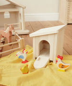 Holztiger wooden small animal shelter toy used as a chicken coop with removable roof and opening door/ramp, set up with a Holztiger hen, chick and cockerel. 