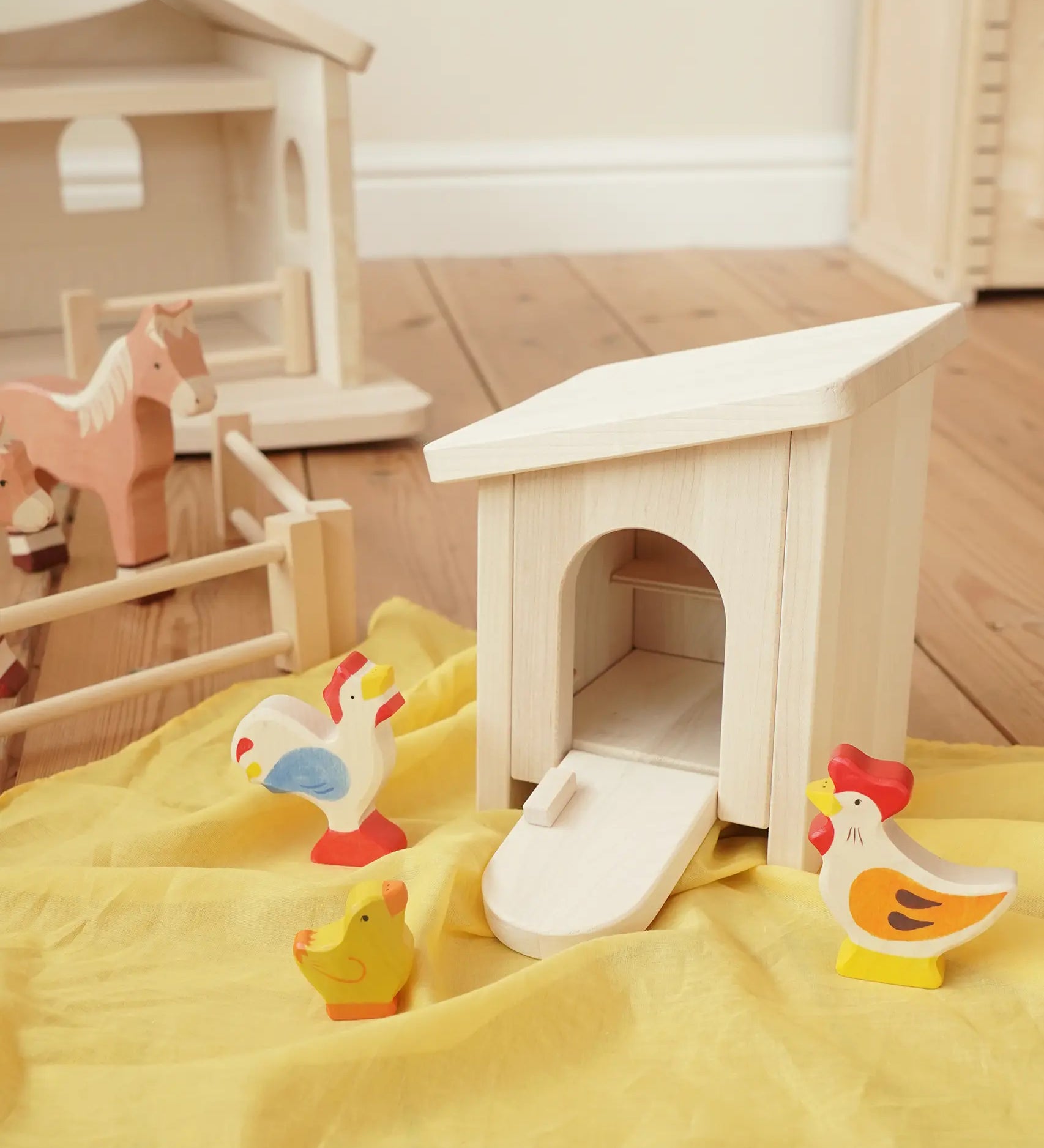 Holztiger wooden small animal shelter toy used as a chicken coop with removable roof and opening door/ramp, set up with a Holztiger hen, chick and cockerel. 