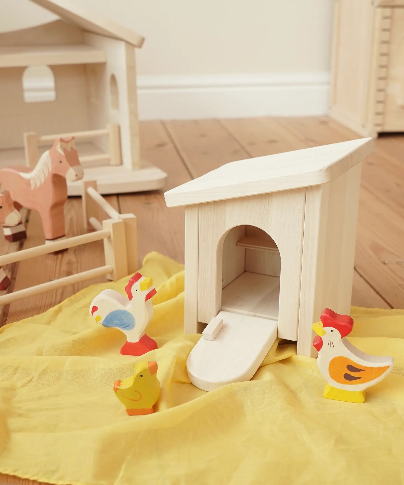 Holztiger wooden small animal shelter toy used as a chicken coop with removable roof and opening door/ramp, set up with a Holztiger hen, chick and cockerel. 