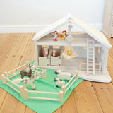 Holztiger Wooden Stable Toy With working Rope Winch, horse stable doors, a ladder and fences. Paired with Holztiger farm animals and a green play cloth from Laura's Play Cotton.