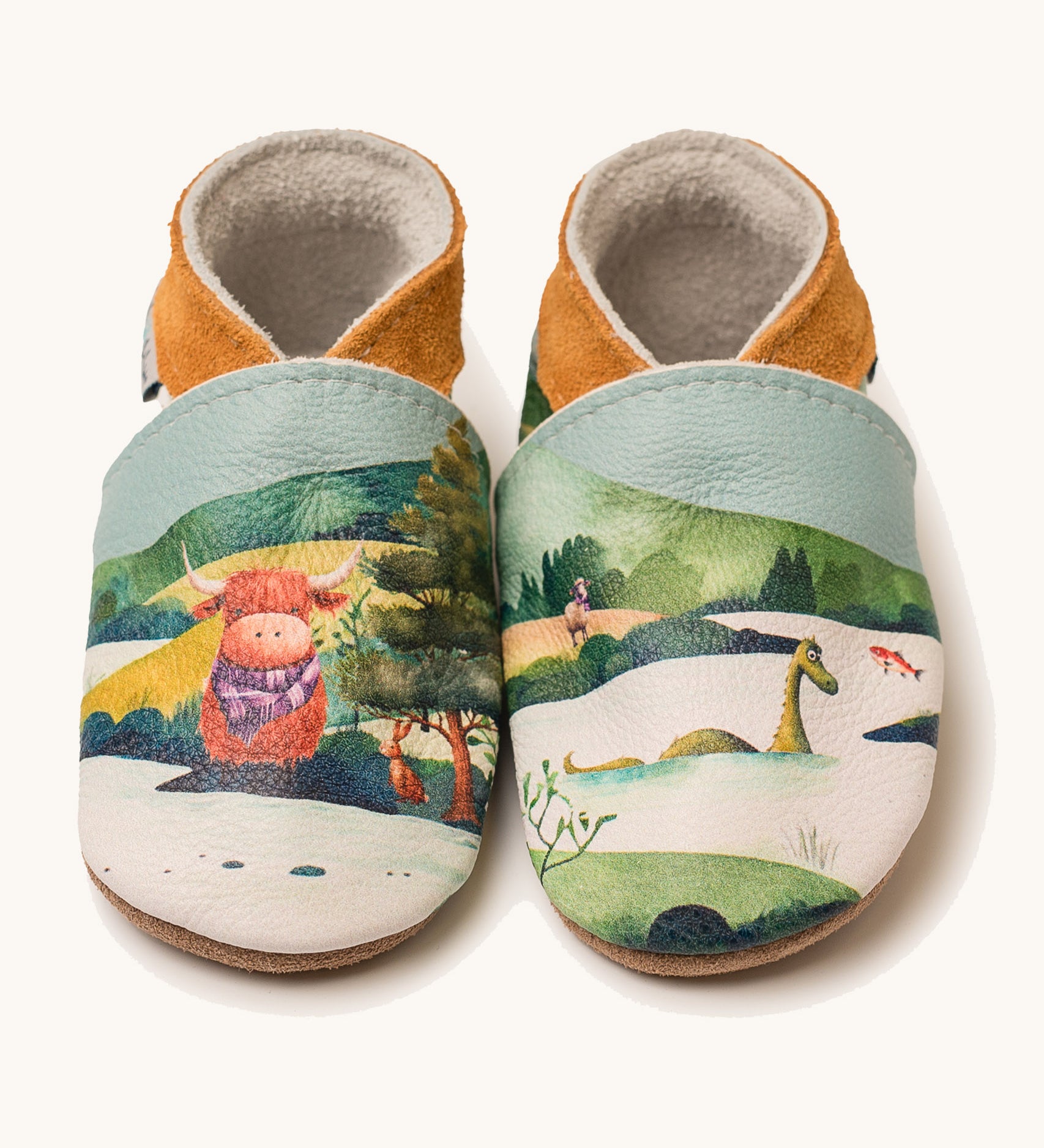 Inch Blue highland cow shoes available at Babipur. A soft baby leather shoe with a playful highland cow and the loch ness monster design. Features elastic ankle cuffs for a secured fit