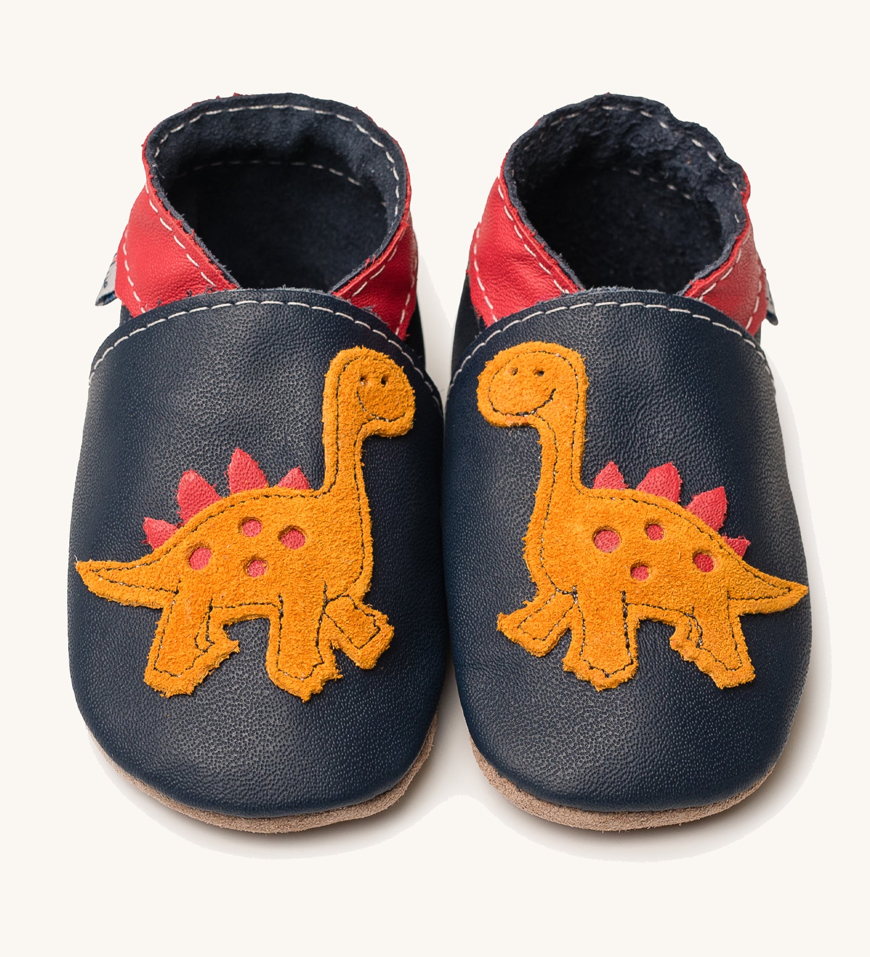 Inch Blue navy dino baby shoes available at Babipur. A soft navy baby leather shoe with a cute playful orange suede dinosaur on each shoe. Features elastic ankle cuffs for a secured fit