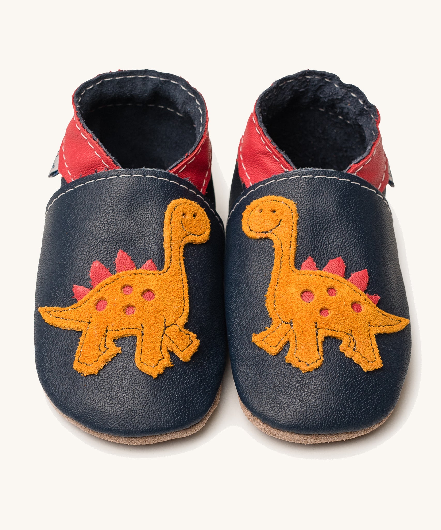 Inch Blue navy dino baby shoes available at Babipur. A soft navy baby leather shoe with a cute playful orange suede dinosaur on each shoe. Features elastic ankle cuffs for a secured fit