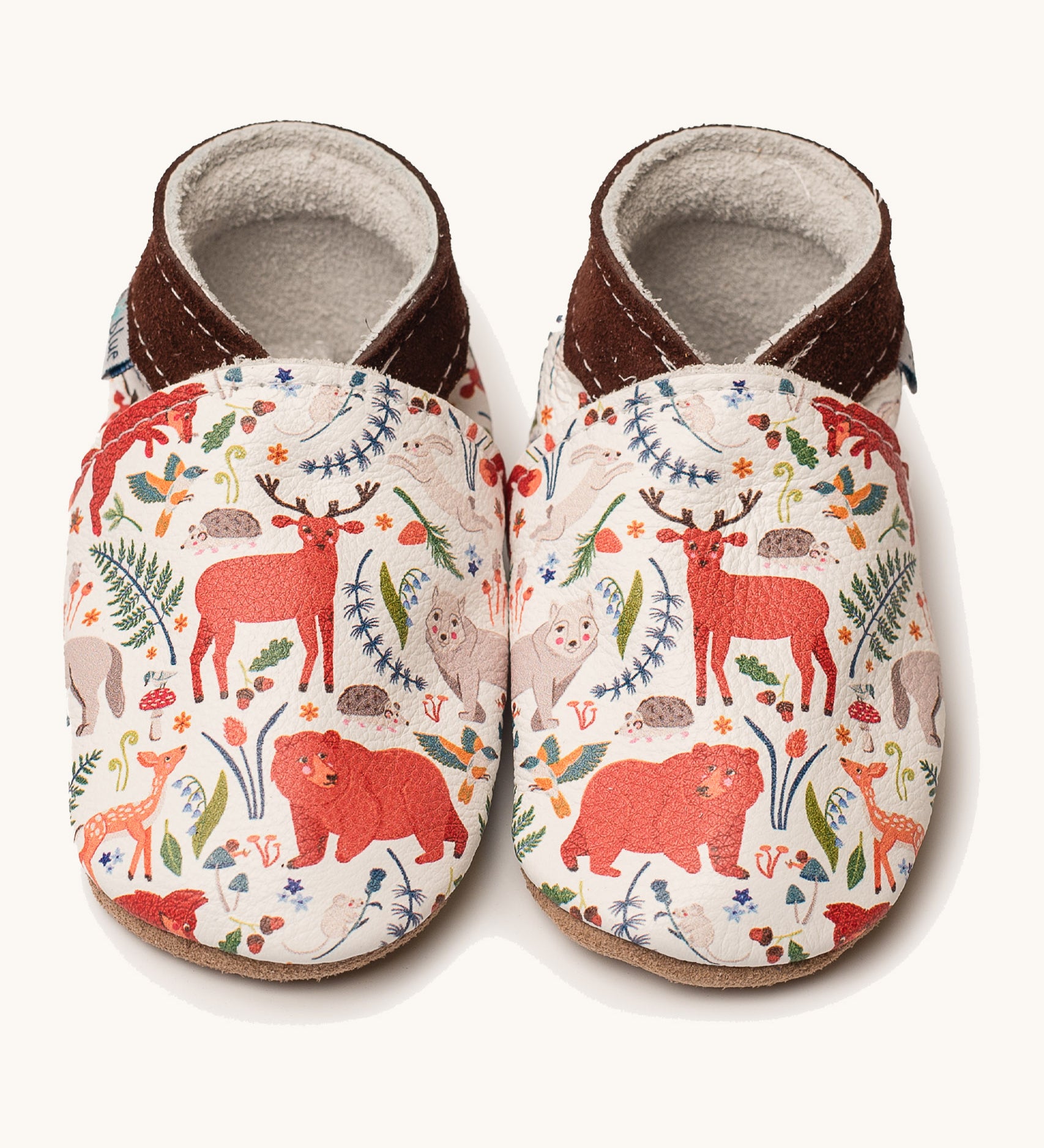 Inch Blue stag & friends shoes available at Babipur. A soft white baby leather shoe with cute pastel coloured stag and woodland animals on each shoe. Features elastic ankle cuffs for a secured fit