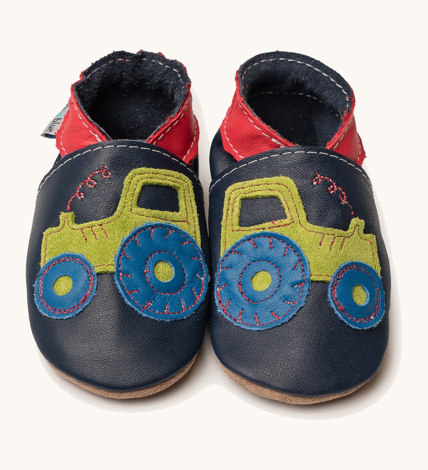 Inch Blue navy tractor baby shoes available at Babipur. A soft navy baby leather shoe with a playful green suede tractor and red collar on each shoe. Features elastic ankle cuffs for a secured fit