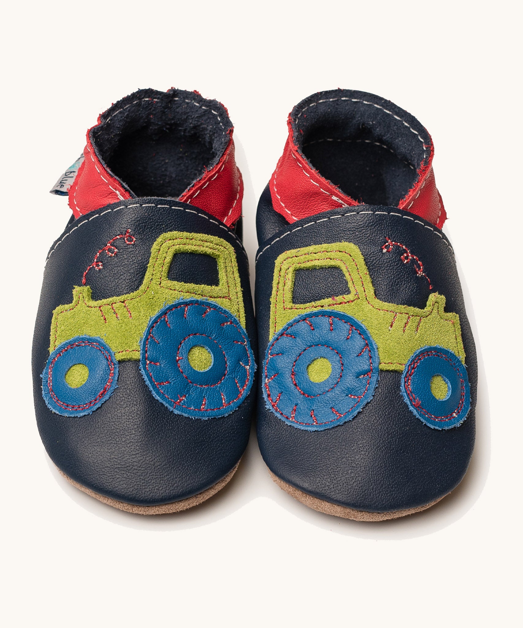 Inch Blue navy tractor baby shoes available at Babipur. A soft navy baby leather shoe with a playful green suede tractor and red collar on each shoe. Features elastic ankle cuffs for a secured fit
