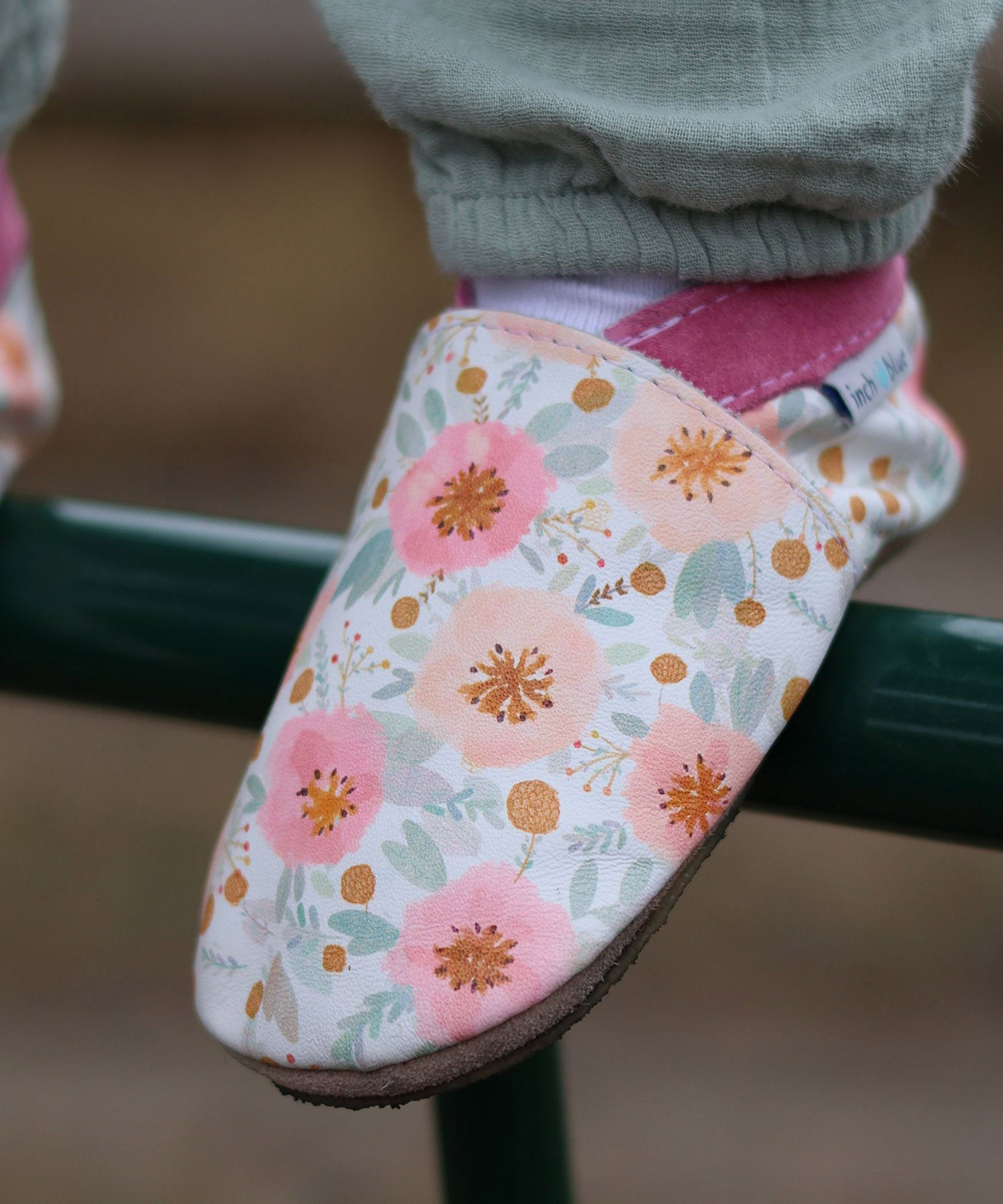 A close up of a child wearing the Inch Blue wildroses shoes available at Babipur showing the cute pastel floral design and pink ankle cuff detail