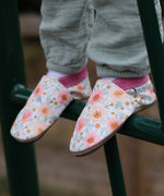 A close up of a child standing on a ladder and wearing the Inch Blue wildroses shoes available at Babipur showing the cute pastel floral design and pink ankle cuff detail