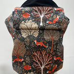 Integra Baby Carrier - Woodland Fox. Woodland Fox is a beautifully illustrated print in soft organic cotton featuring woodland trees in autumnal tones and red foxes on a black background.