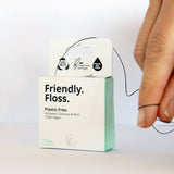 An adult pulling the Jack N Jill friendly dental floss available at Babipur. A 100% vegan waxed bamboo activated charcoal & mint dental floss.