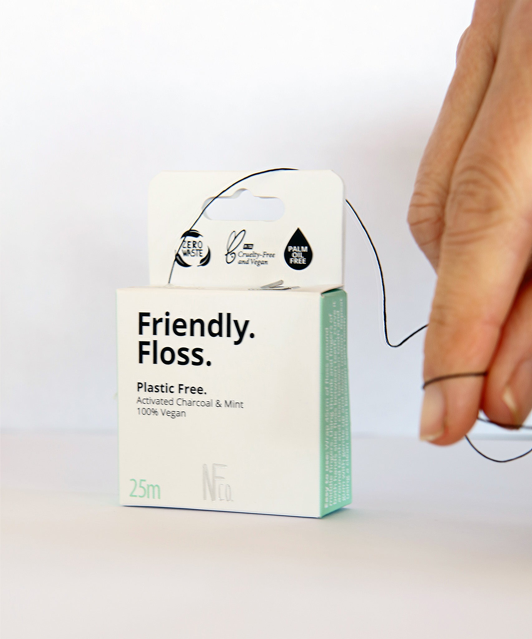 An adult pulling the Jack N Jill friendly dental floss available at Babipur. A 100% vegan waxed bamboo activated charcoal & mint dental floss.