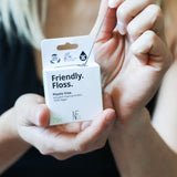 An adult pulling the Jack N Jill friendly dental floss available at Babipur. 100% vegan waxed bamboo activated charcoal & mint dental floss. Features a small cutter on the top of the box for easy cutting.
