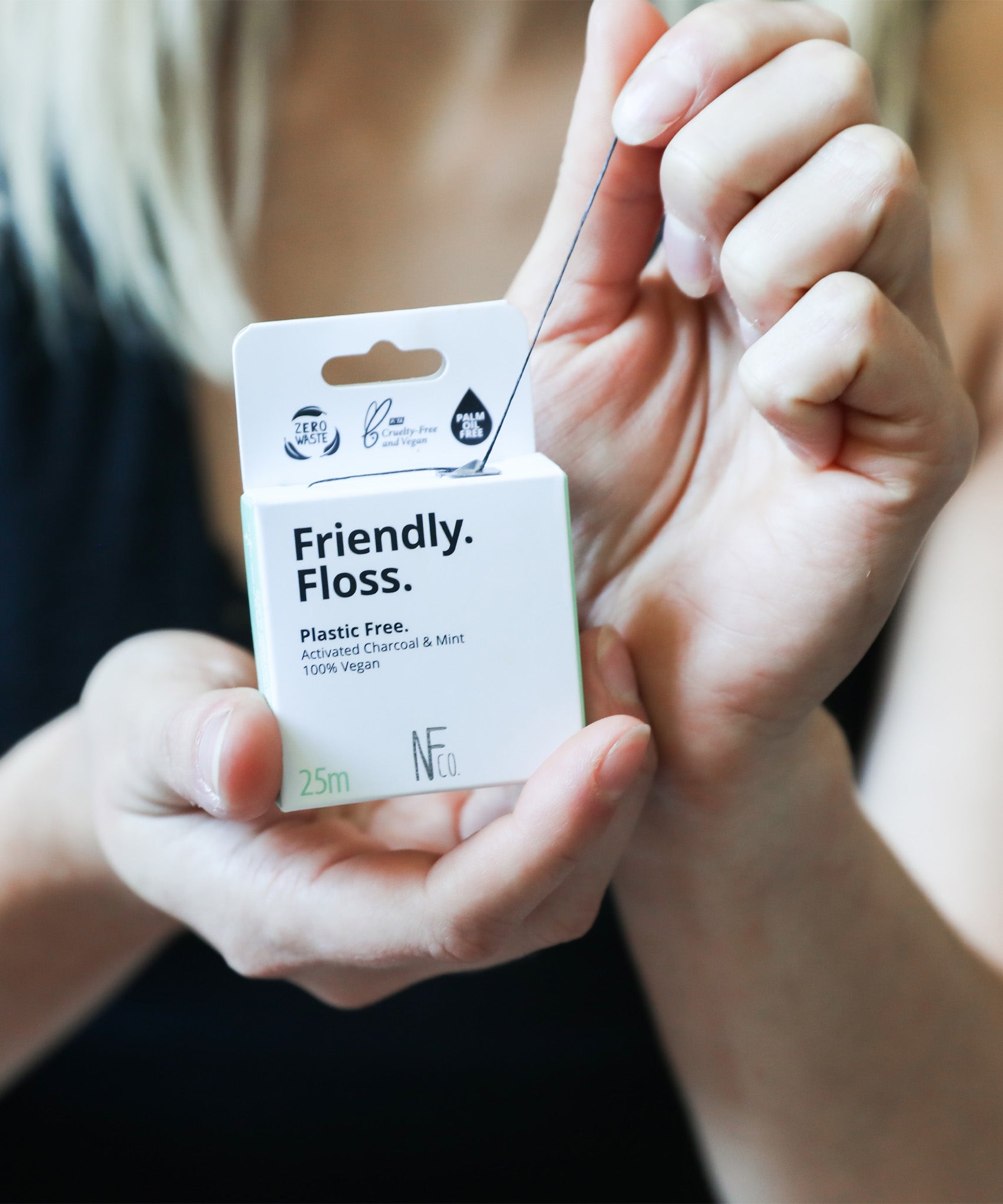 An adult pulling the Jack N Jill friendly dental floss available at Babipur. 100% vegan waxed bamboo activated charcoal & mint dental floss. Features a small cutter on the top of the box for easy cutting.