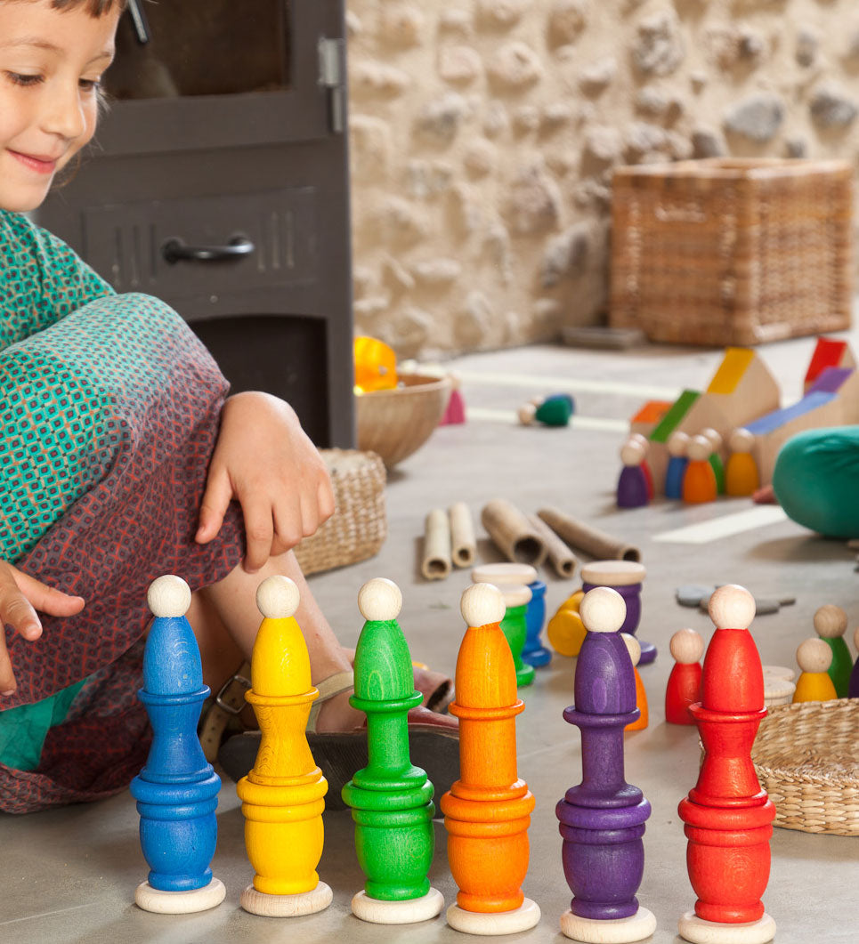A child playing with Grapat wooden toys, Nins, spools, mates and coins have been stacked on top of each other. Grapat have a wide range of wooden toys and loose parts available at Babipur. 