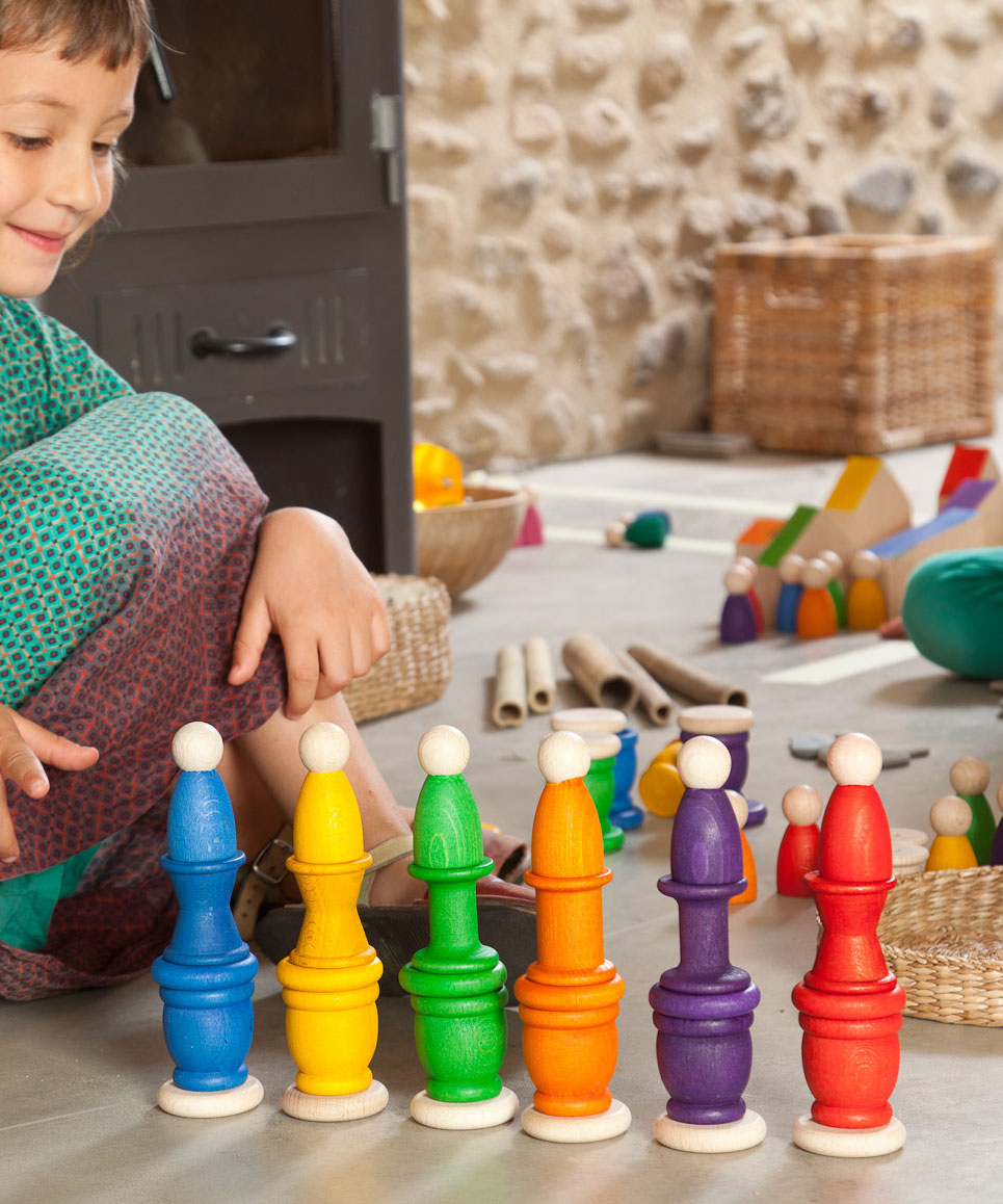 A child playing with Grapat wooden toys, Nins, spools, mates and coins have been stacked on top of each other. Grapat have a wide range of wooden toys and loose parts available at Babipur. 