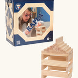 A box of 120 Kapla natural wooden construction planks. A stack can be seen next to the box 