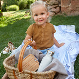 A child holding a basket with a Lassig Stainless Steel Bamboo Lunchbox with an Adventure design inside with a water bottle. The words let's be wild are written on the bamboo lid. This children's divided lunchbox is part of a wide range of food storage solutions available at Babipur.