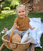 A child holding a basket with a Lassig Stainless Steel Bamboo Lunchbox with an Adventure design inside with a water bottle. The words let's be wild are written on the bamboo lid. This children's divided lunchbox is part of a wide range of food storage solutions available at Babipur.