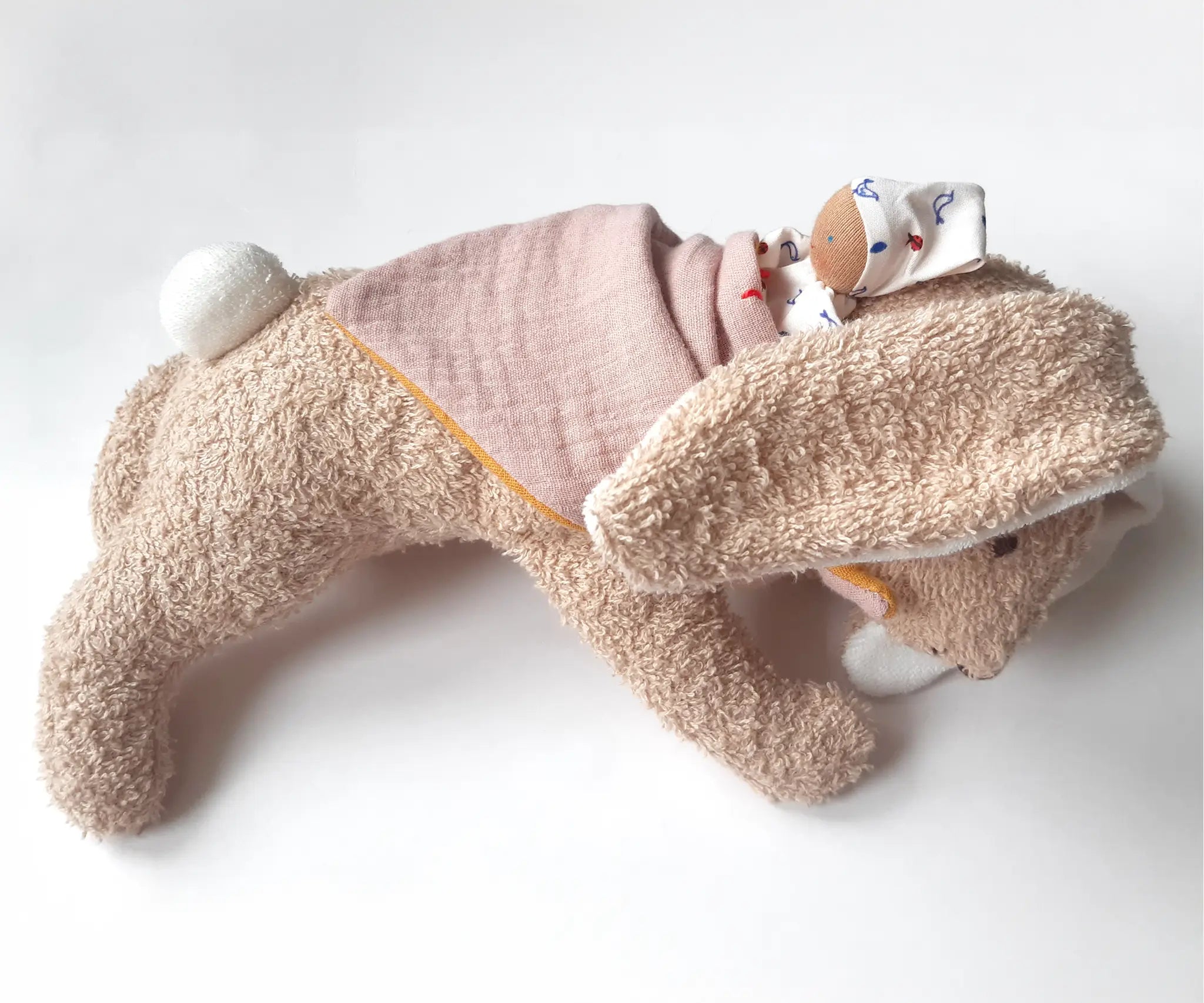 Kathe Kruse holly lying rabbit comforter with small white waldorf doll on the back wrapped in the muslin bib