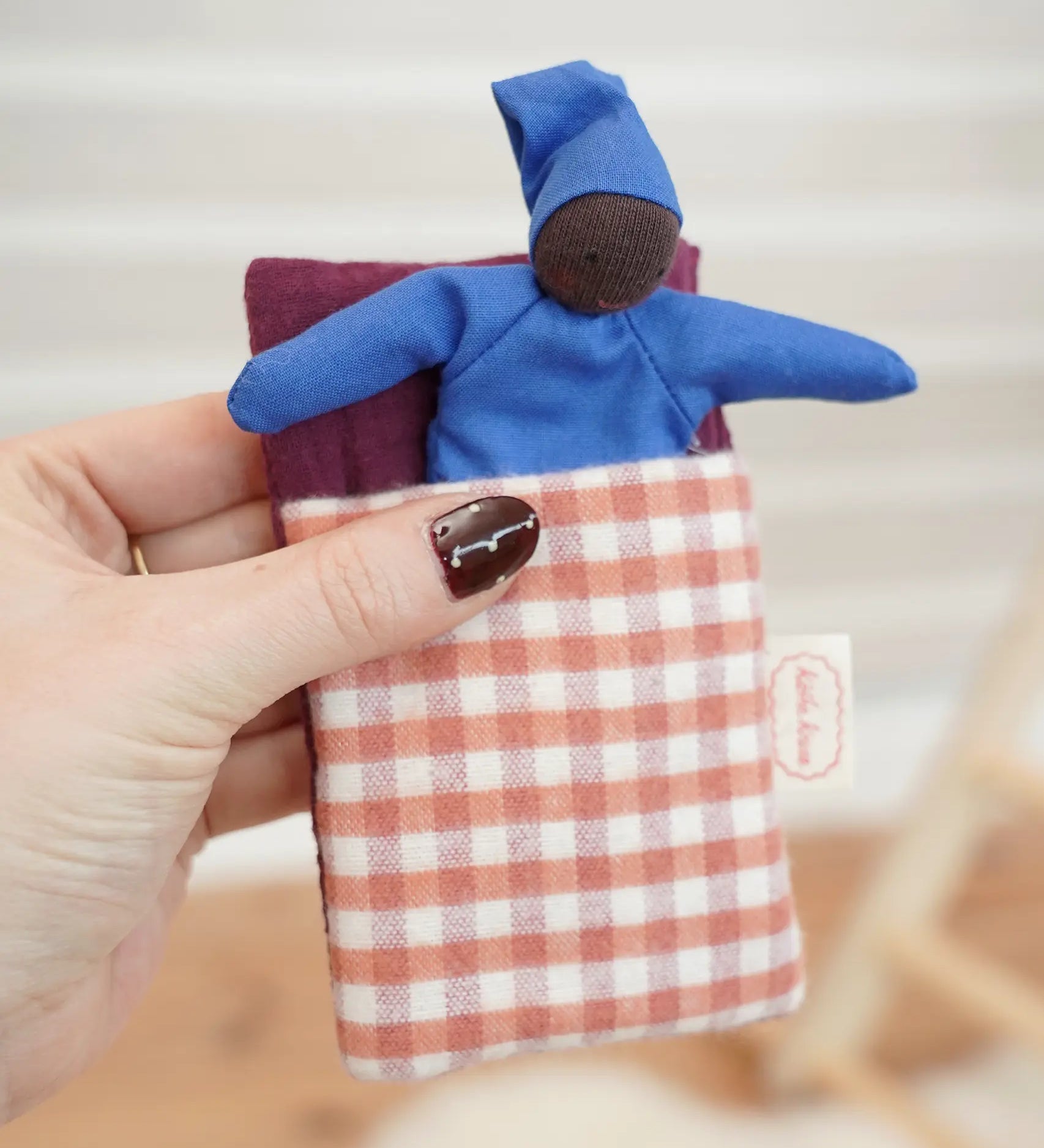 Kathe Kruse baby Waldorf Doll black skin with sleeping bag in red check.