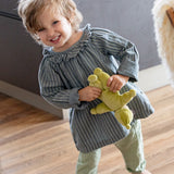 Child playing with Kathe Kruse light green Lolo moss Waldorf doll in a dining room