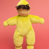 Kathe Kruse light green Lolo moss Waldorf doll with a towelling outfit standing in front of a light red background