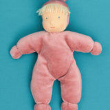 Kathe Kruse Lolo Rose waldorf doll showing a light pink towelling outfit lying flat on a blue surface