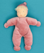 Kathe Kruse Lolo Rose waldorf doll showing a light pink towelling outfit lying flat on a blue surface