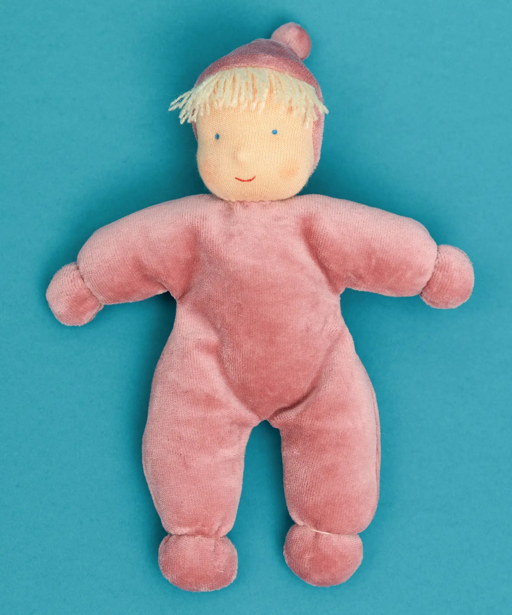 Kathe Kruse Lolo Rose waldorf doll showing a light pink towelling outfit lying flat on a blue surface
