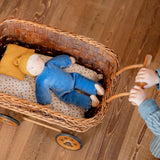 Child pushing a wicket pram with a Kathe kruse cloud nana waldorf doll lying inside 